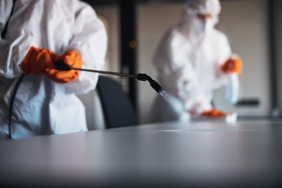 Femme utilisant un distributeur de gel hydroalcoolique, mains positionnées pour recevoir le produit désinfectant